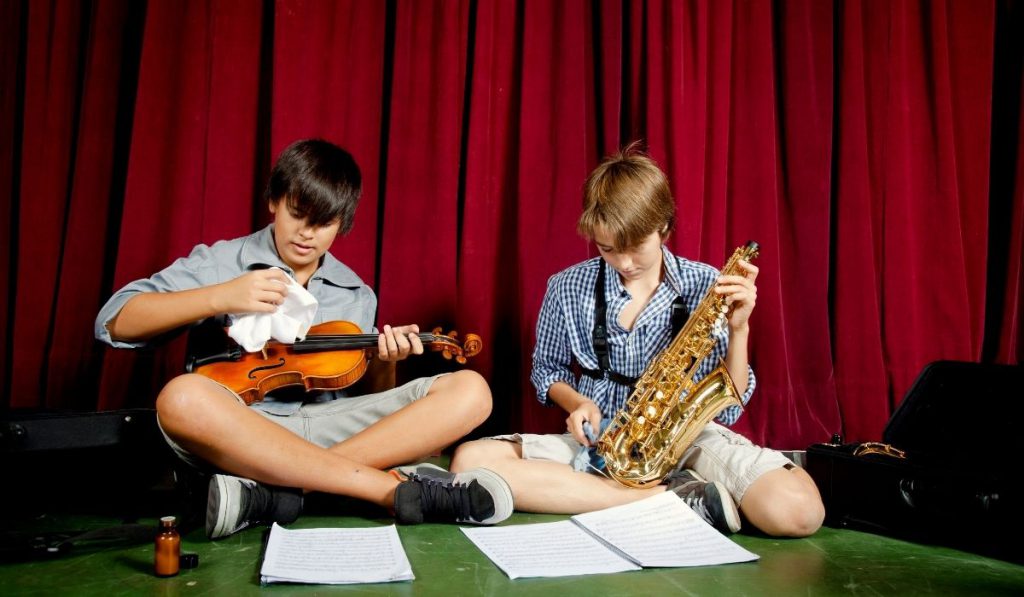two boys cleaning their musical instruments
