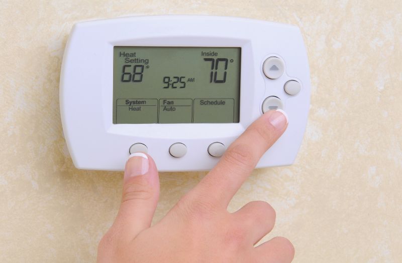 woman adjusting a thermostat